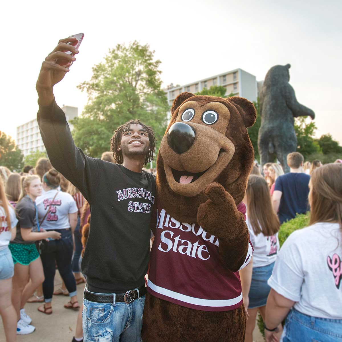 Student taking a selfie with Boomer Bear